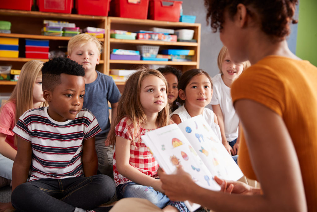 Elementary students listening to adult read