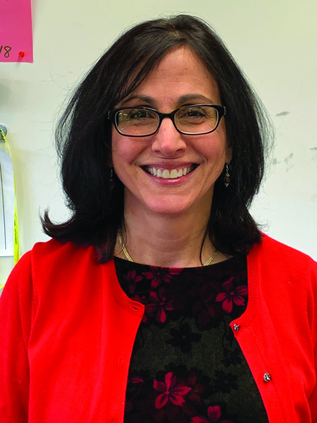 White woman wearing glasses and a red cardigan looks at the camera