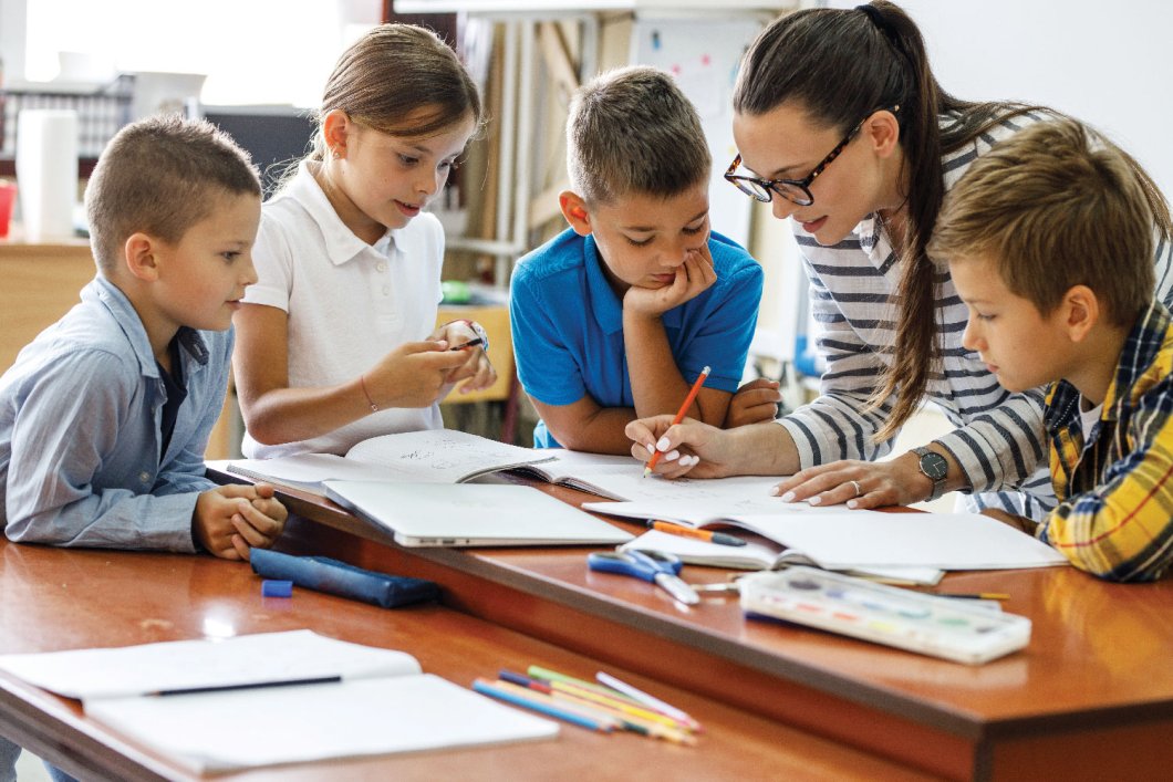 Female teacher reviewing work with four students.