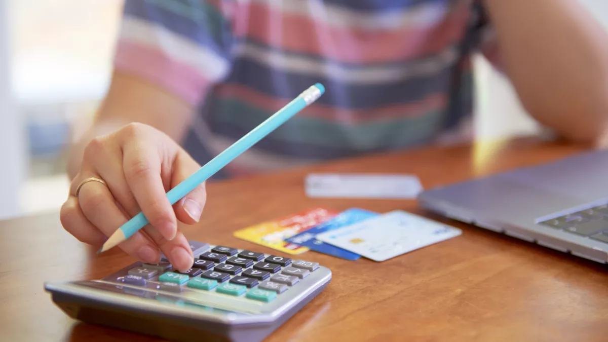 Person with a calculator and credit cards deals with financial issues.