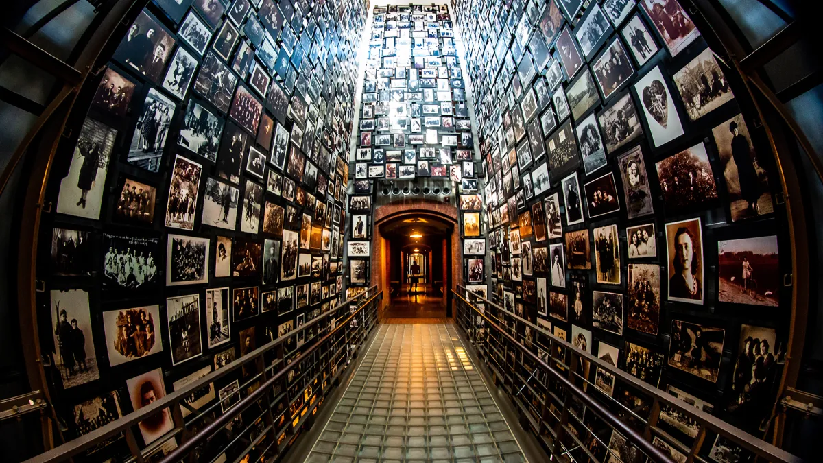 US Holocaust Museum photo of a hallway with floor to ceiling photographs of concentration camp victirms