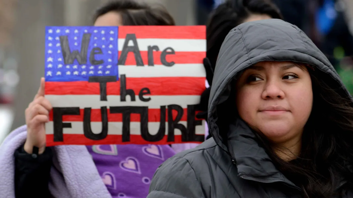 Woman outside holding a sign that says "we are the future" in front of an American flag