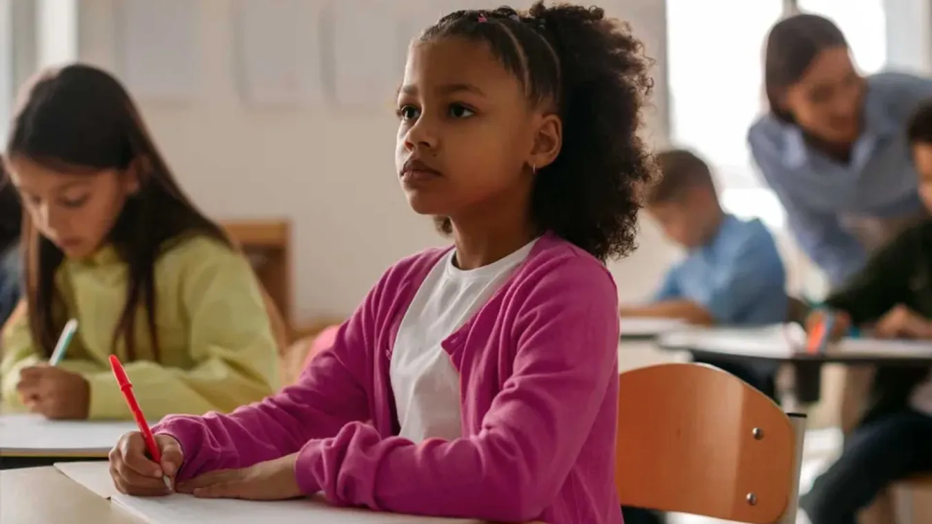 Young student at a desk looking up
