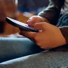 closeup of student hands holding cellphone in lap