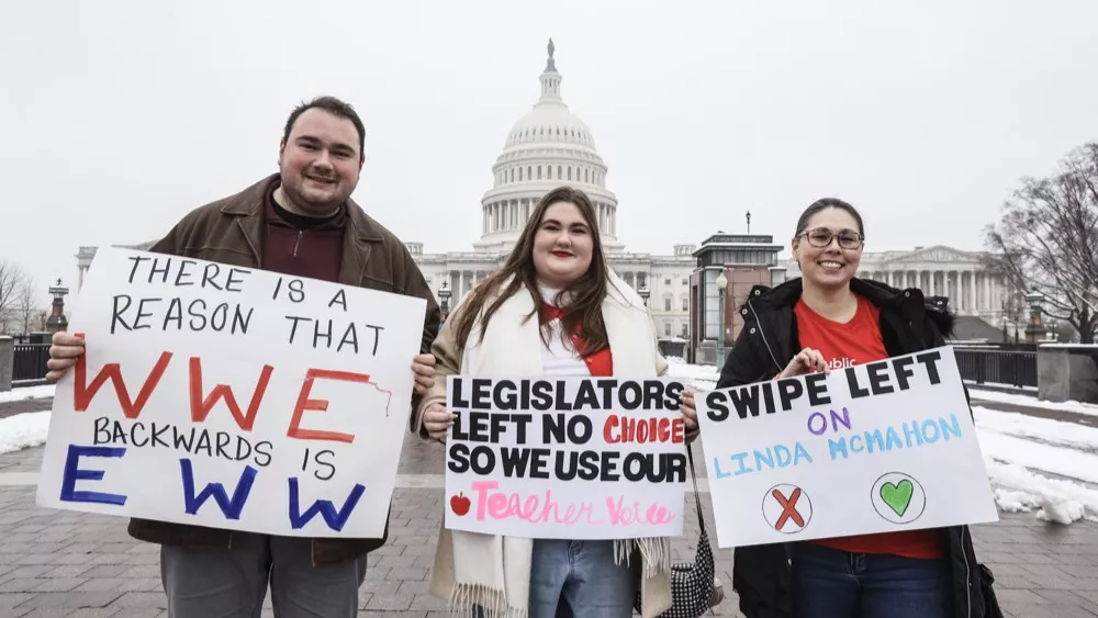 Three Aspiring Educators stand holding pro-public education signs in front of the U.S. Capitol building.