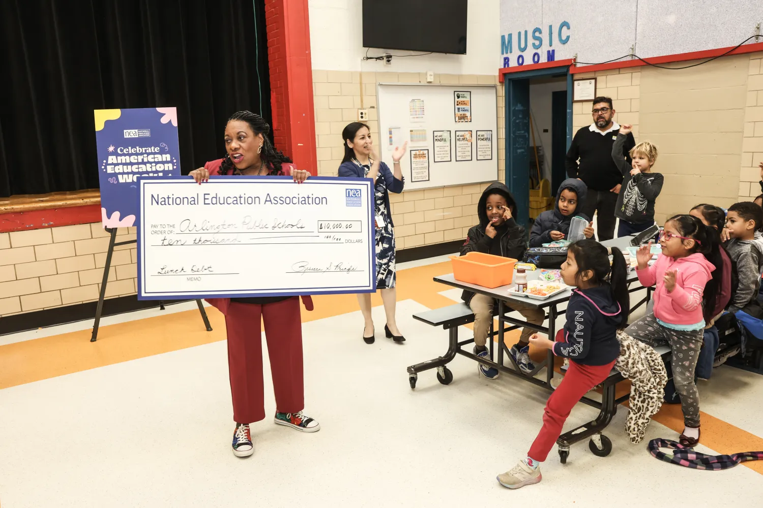 With cheers from students, Pringle presents $10,000 to Arlington Public Schools to help pay down unpaid student lunch balances.