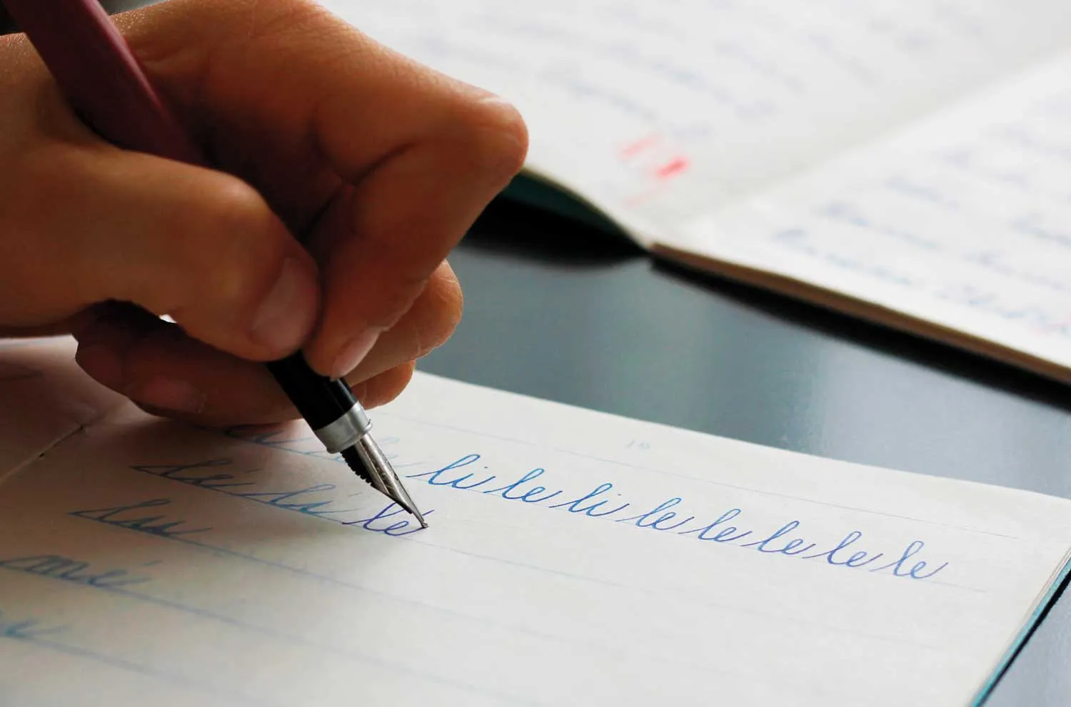 Student writing in cursive with a fountain pen.