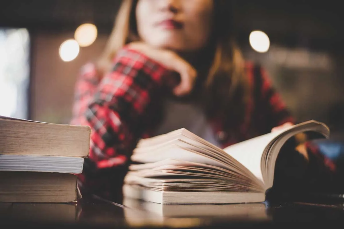 Female student reading a paperback book.