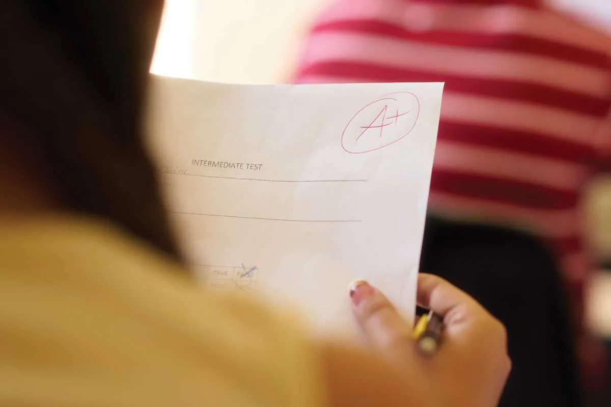 View of an A+ graded test from behind a female student.
