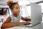 An African American girl uses a laptop