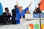 NEA Executive Director on event stage, hands raised