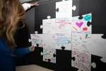 Photos of oversized puzzle pieces with messages of why future teachers choose to teach. 