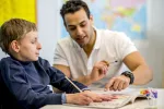 Child in wheelchair working with a teacher at a desk