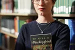 Alex Johnson stands in her college library