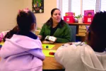 preschool teacher Rita Bamba sits at a table with students using pictures and blocks to teach