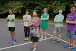 six middle school students stand outside with arms folded