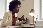 Black professional woman sits at a desk and participates in an online meeting