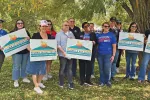 10 Nevada State Education Association members stand outside holding signs with NEA president Becky Pringle and Comedien Patton Oswalt