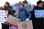 protesters hold signs in support of public schools outside the nation's Capitol in February 2025