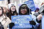 People united in a demonstration, displaying signs that show the importance of safeguarding students and public education.