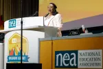 NEA President Becky Pringle stands at a lecturn to address NEA delegates