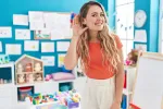 woman teacher stands in her classroom with a hand behind her ear to signal she's listening