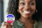 Black women smiling and holding a Your Vote Matters sticker.