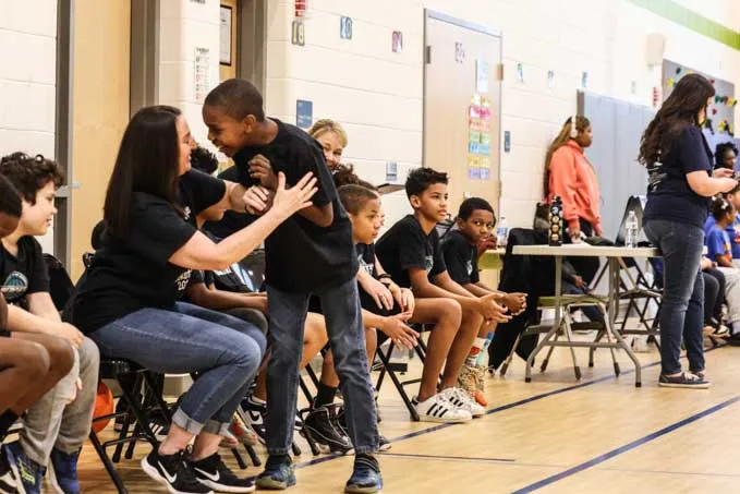 Male student celebrating with an educator on the bench
