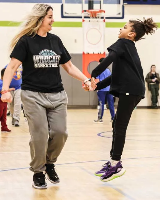 Female student and female educator jumping.
