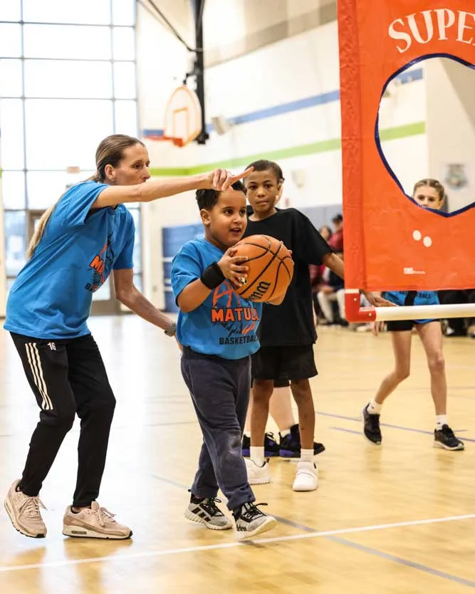 IDEA students with a teacher assisting around a vertical banner with a hole to shoot a ball through.