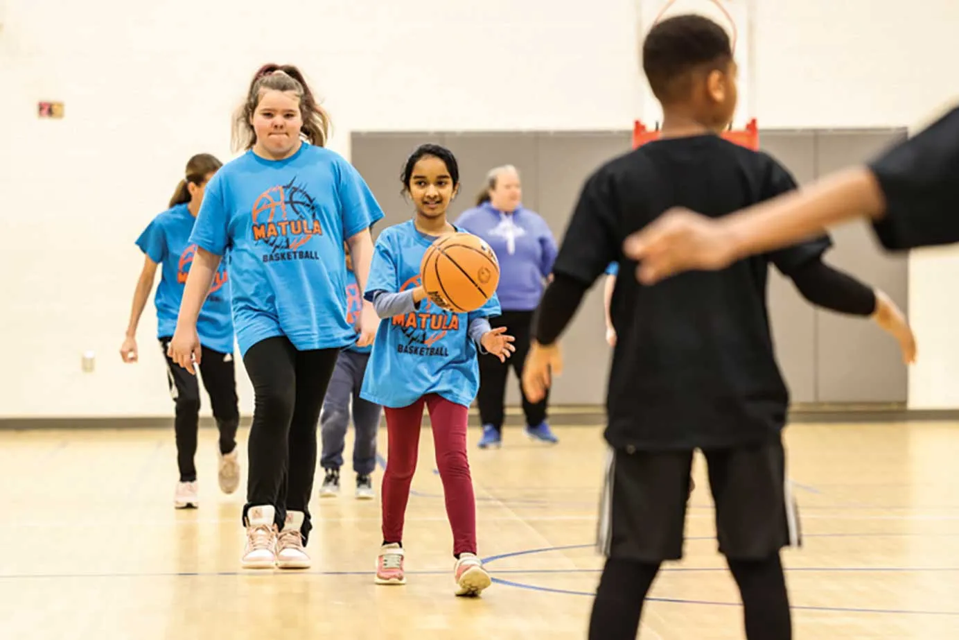 IDEA students dribbling a basketball towards defenders.