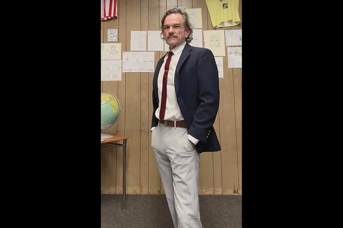 Mr. Ward in a dark blazer, white shirt with a red tie, and light pants.