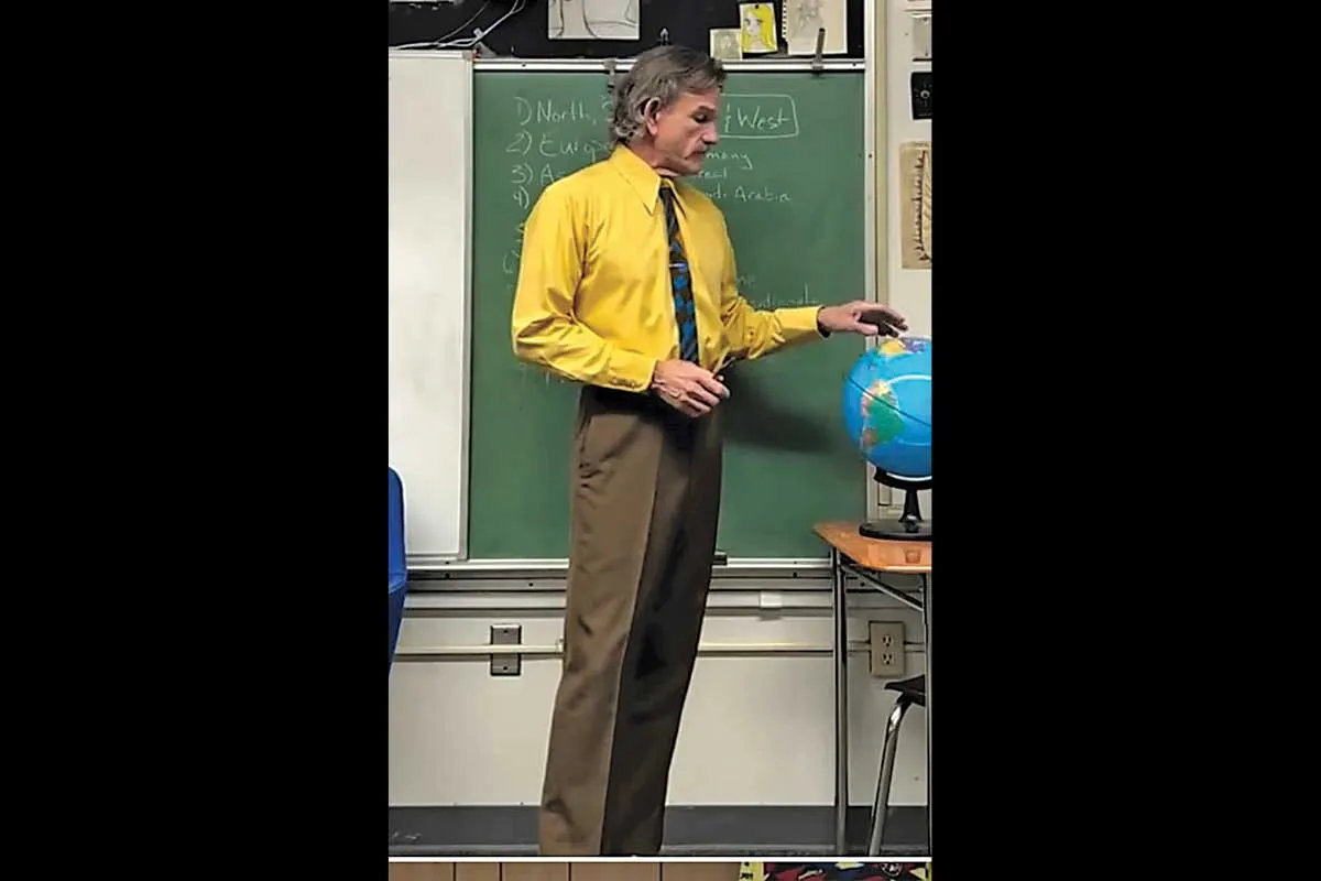 Mr. Ward wearing a yellow shirt with brown pants.