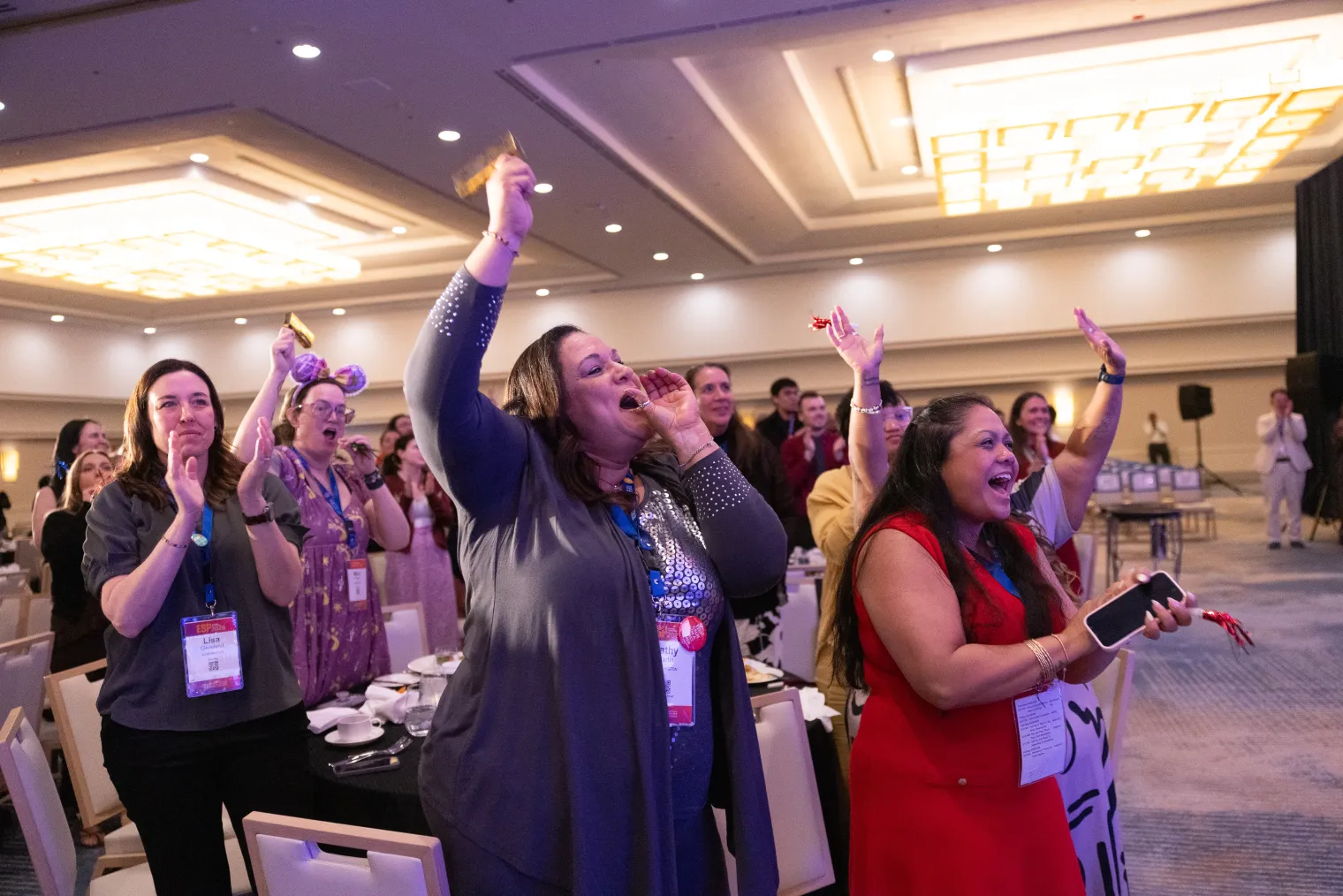 A crowd of people cheering, clapping, and raising their hands