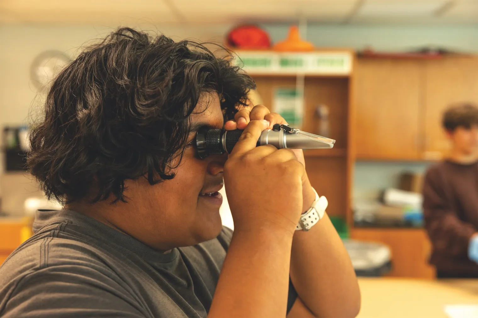 Student holding a refractometer up to his eye