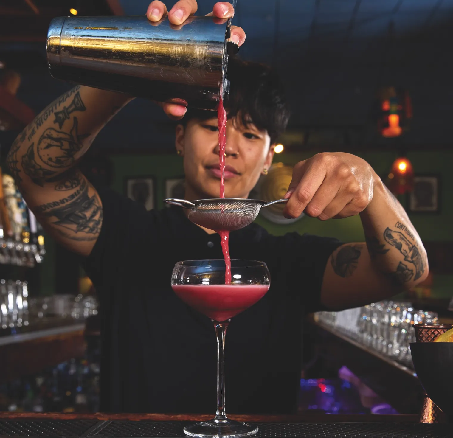 Lisa Coe behind bar, mixing cocktails