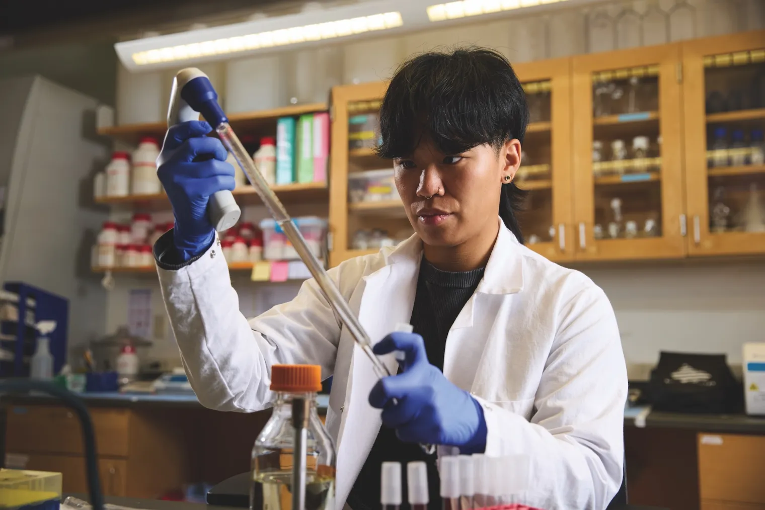 Lisa Coe in lab coat with pipette