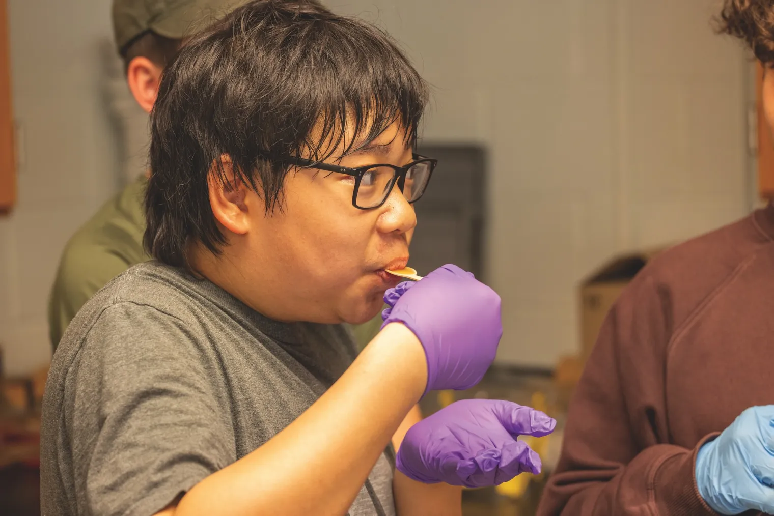 Student tasting honey on small bamboo spoon