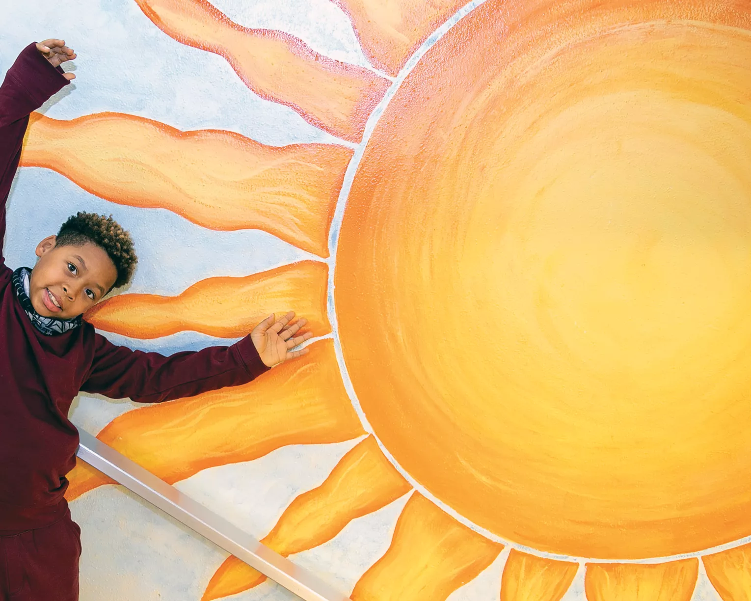 student posing with school mural