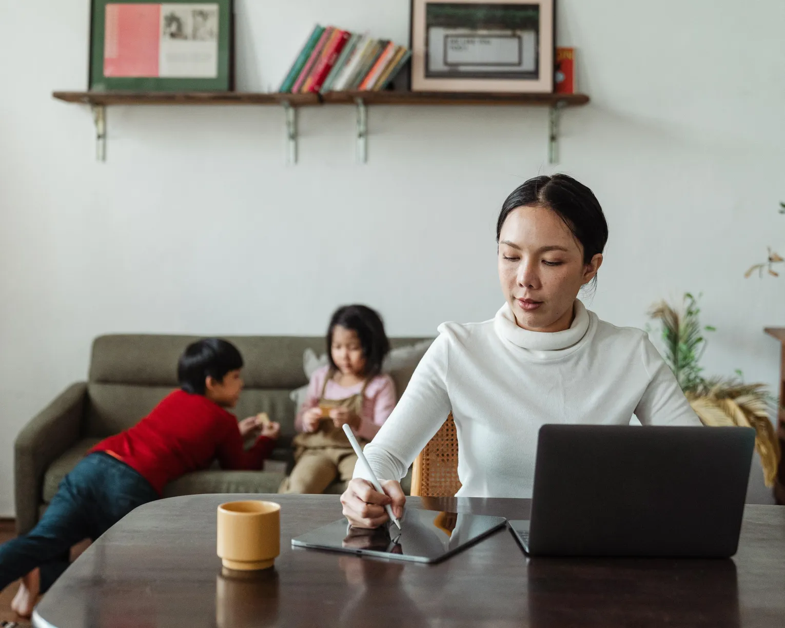 Adult on computer in foreground, children playing in background.