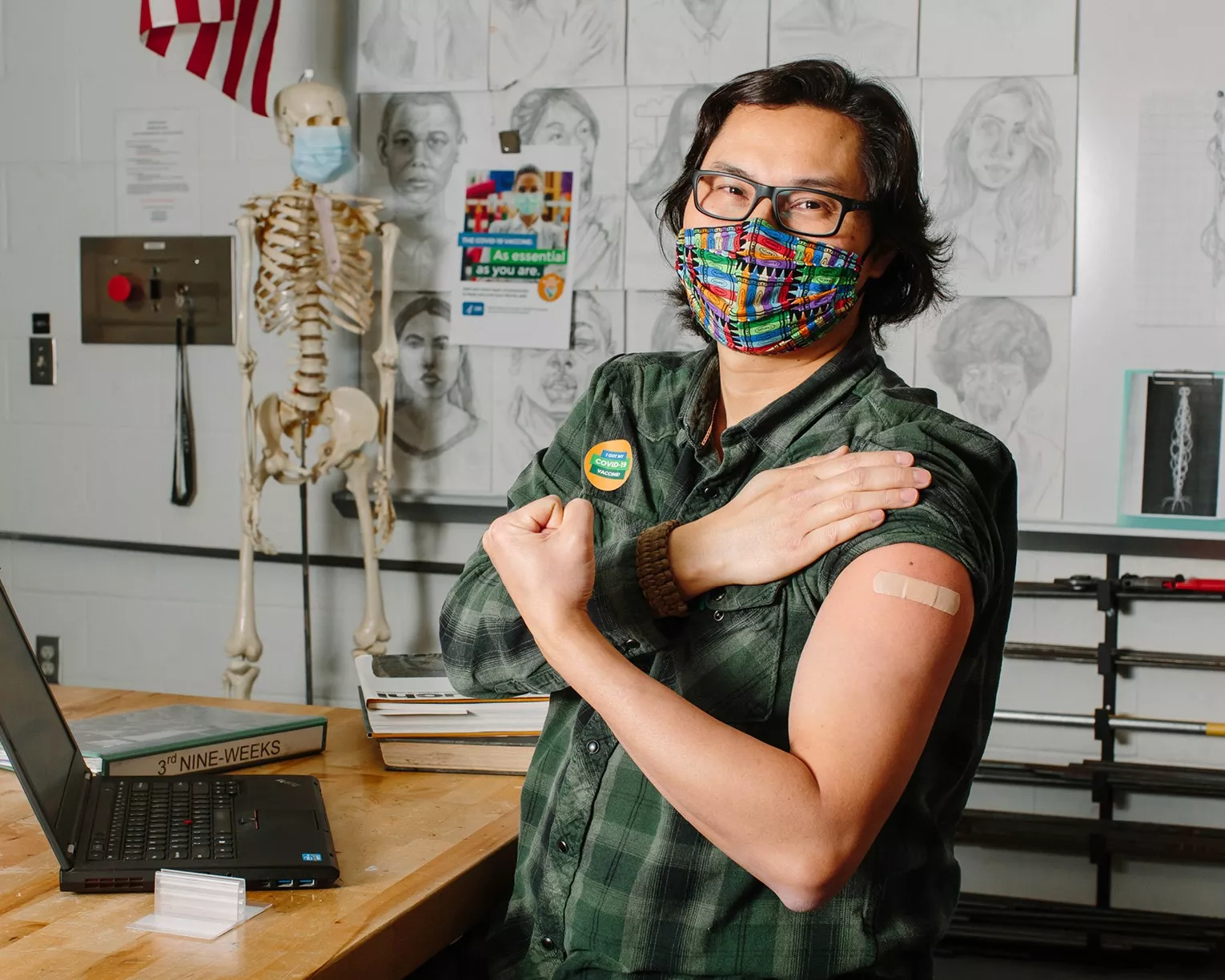 person in a classroom flexing their arm with a bandaid on it