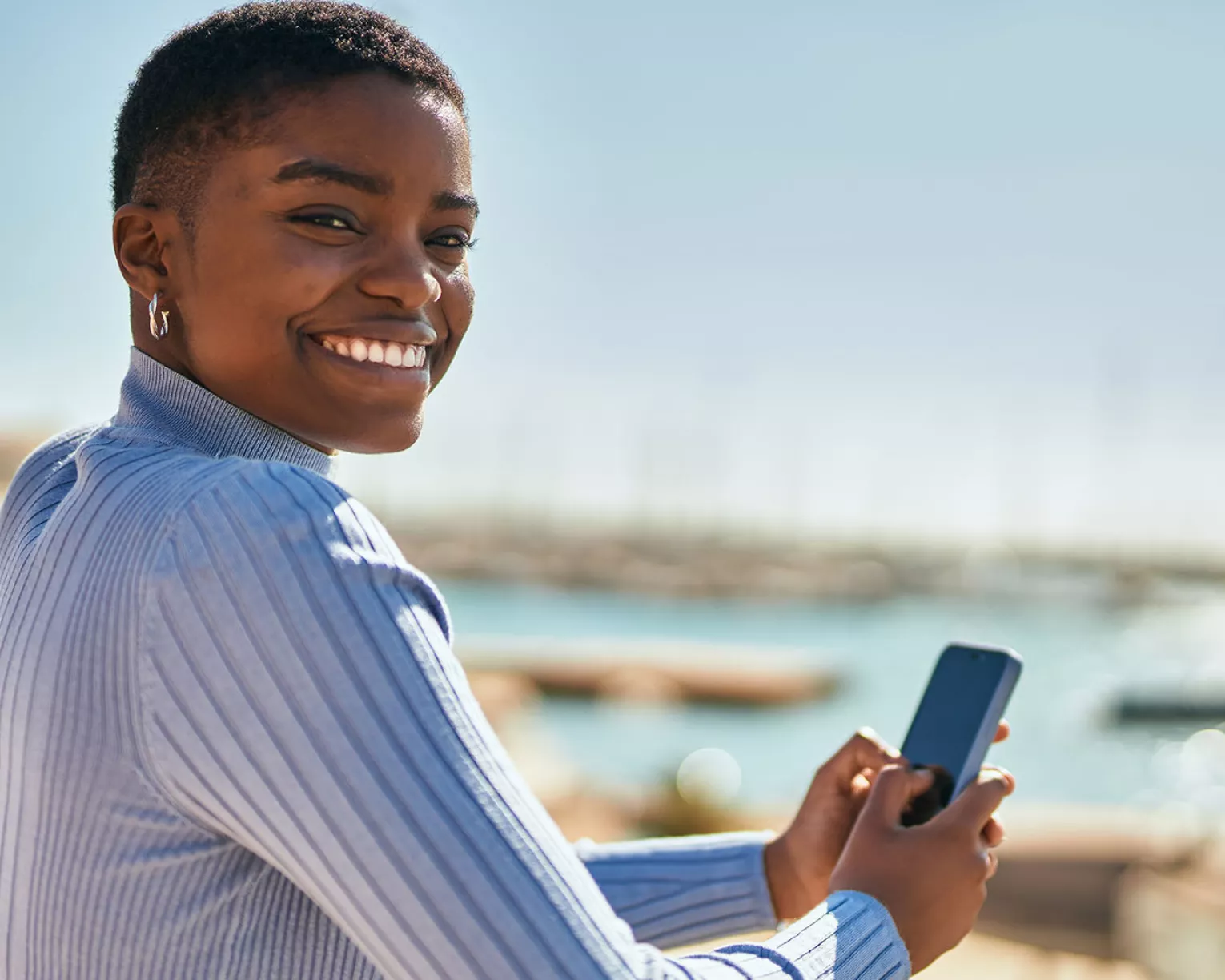Black woman leaning on railing and texting on her mobile phone