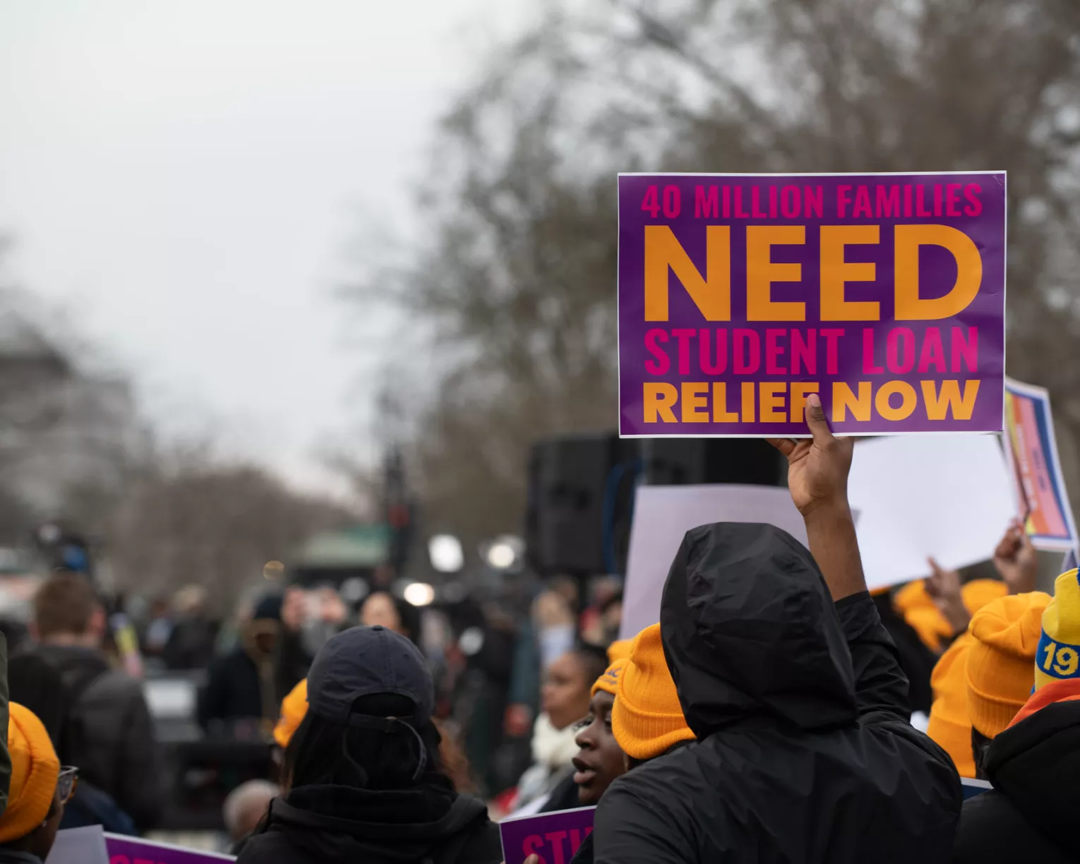 Sign held up at rally saying 40 million families need student loan relief now.