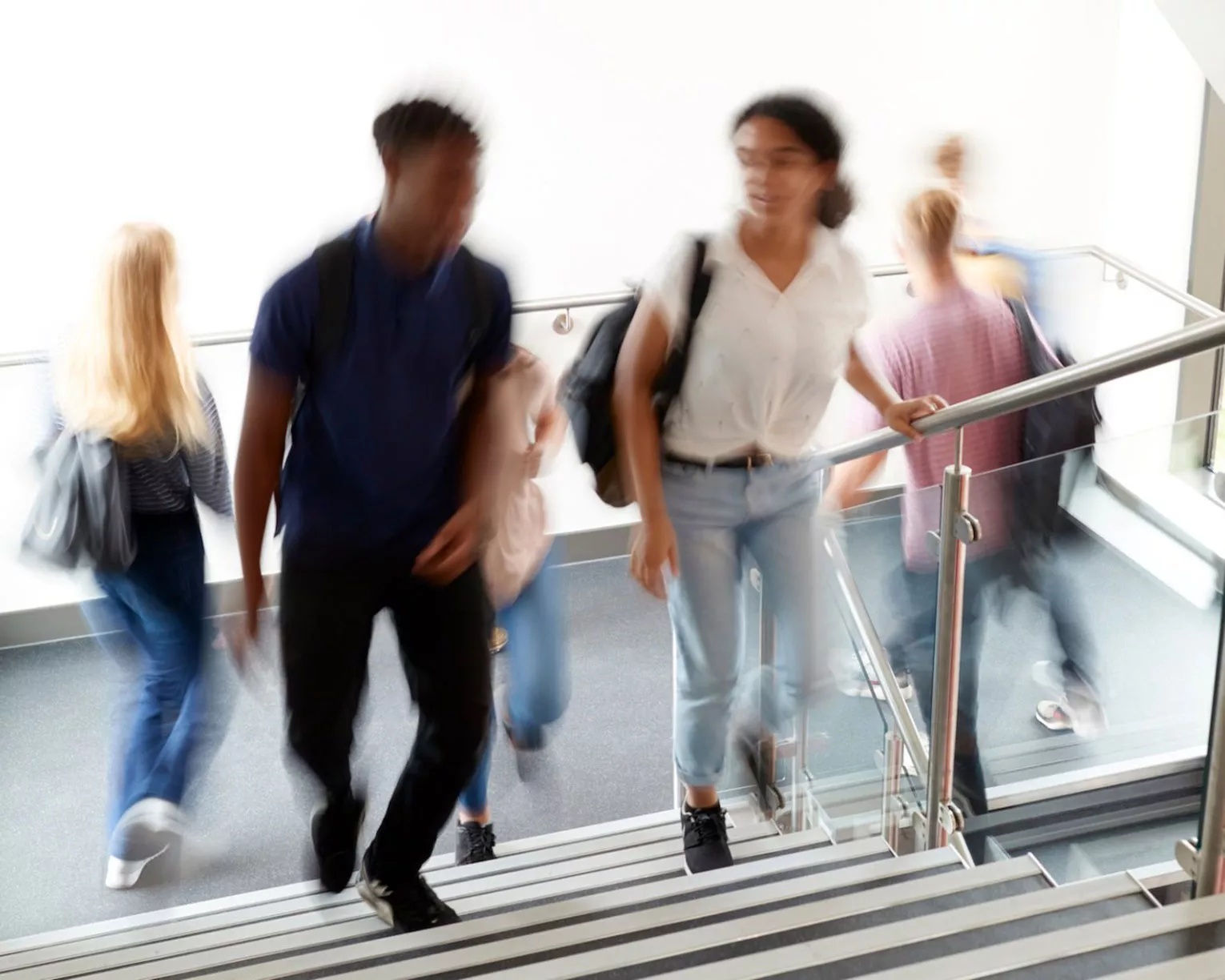 A male and female student ascend a staircase in a school
