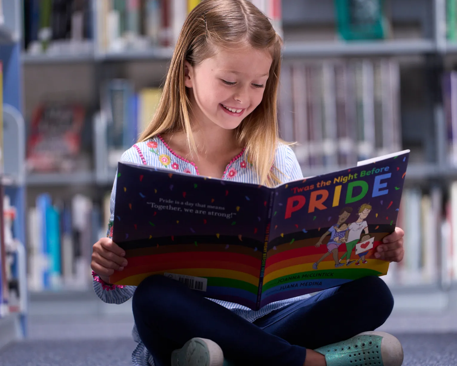 young girl in the library reading a copy of The Night Before Pride