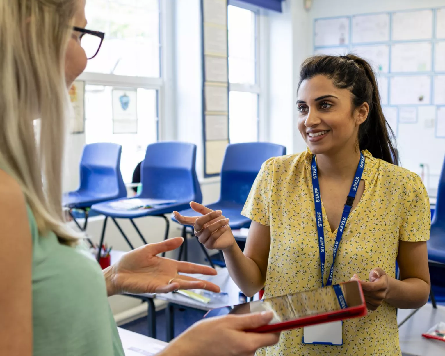Educators stand in classroom talking over an iPad