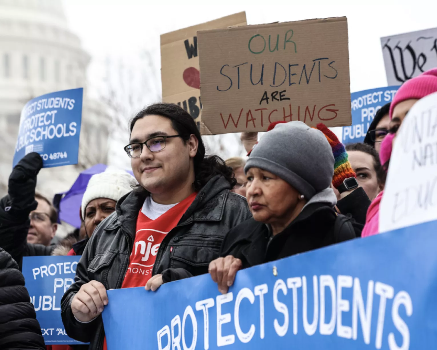 A crowd of people holding various signs about supporting public education.
