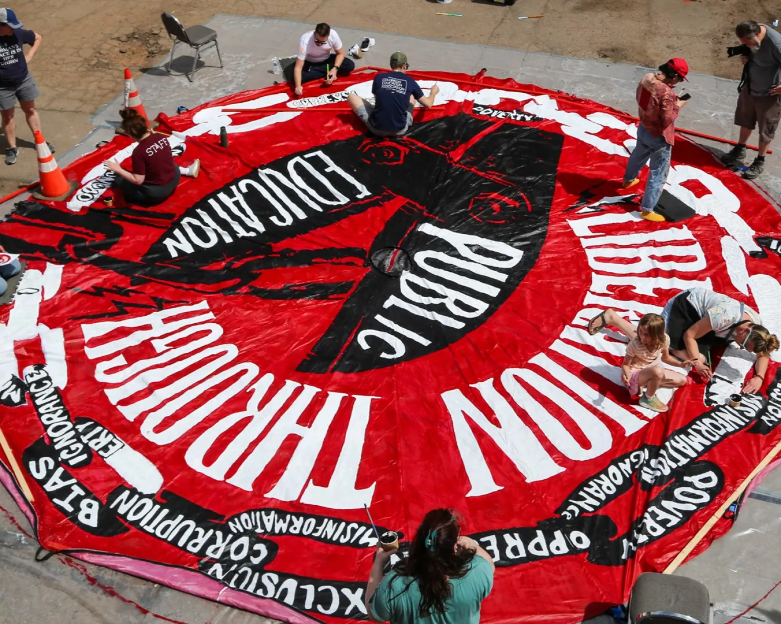 Educators and allies work together on a large piece of public art with pro-public education images.