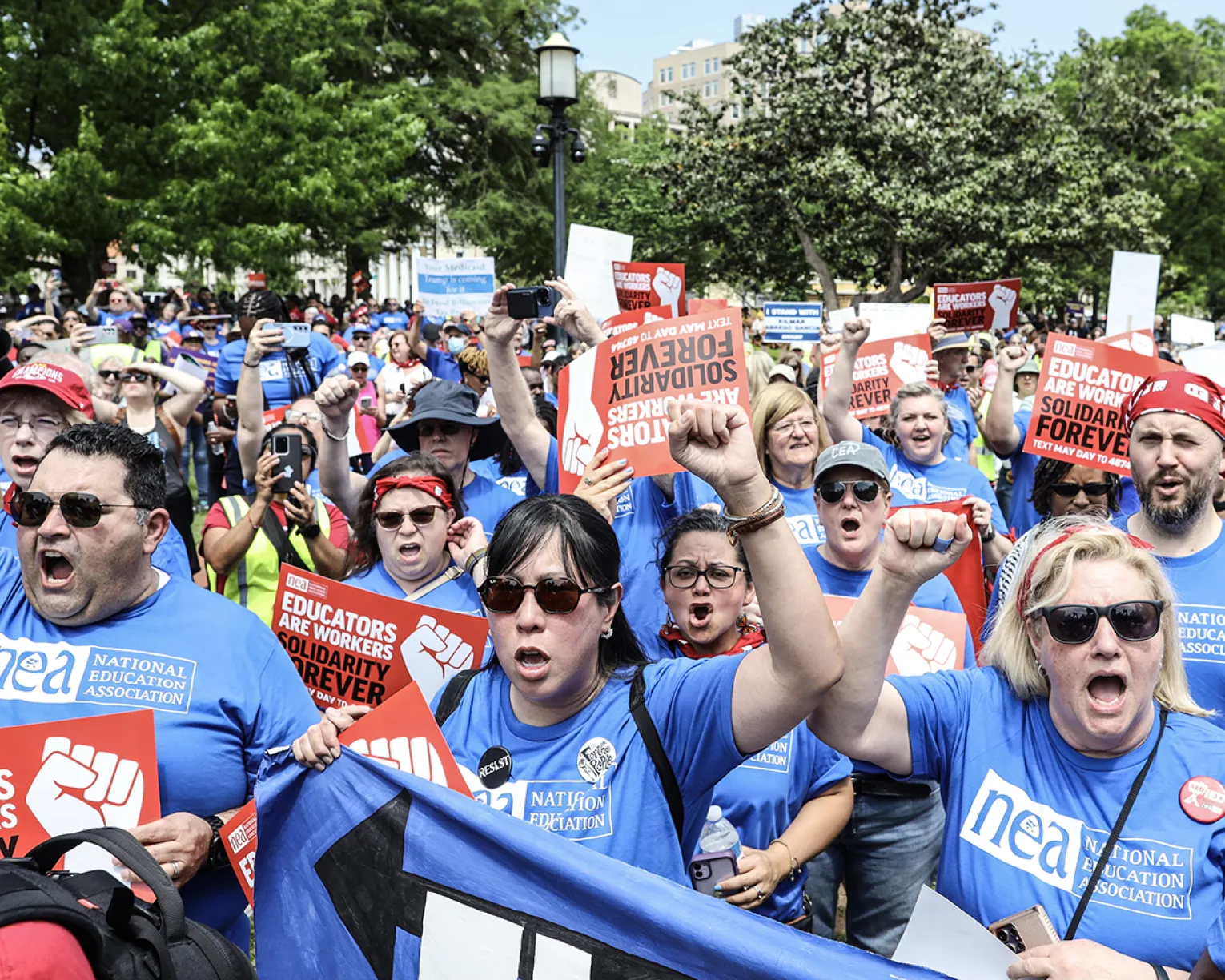 Noel Candelaria and NEA Board Members in blue t-shirts cheer in the crowd at the May Day rally in 2025