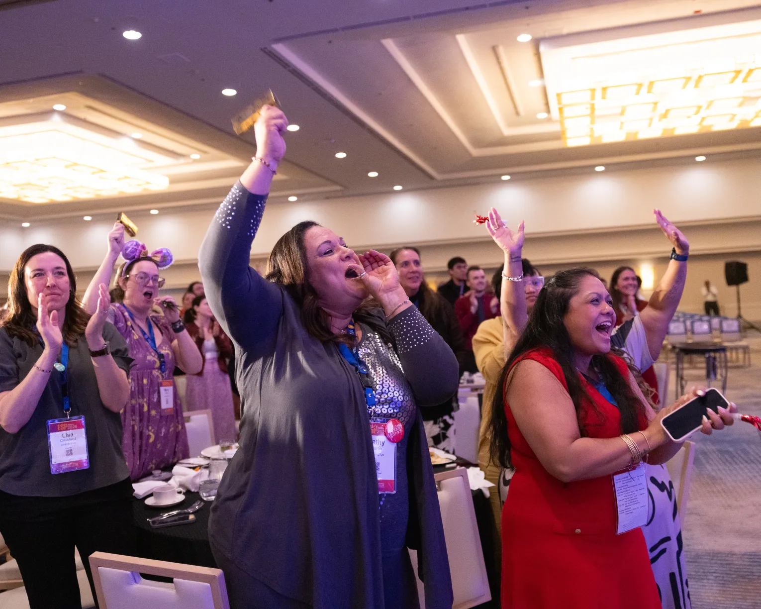 A crowd of people cheering, clapping, and raising their hands